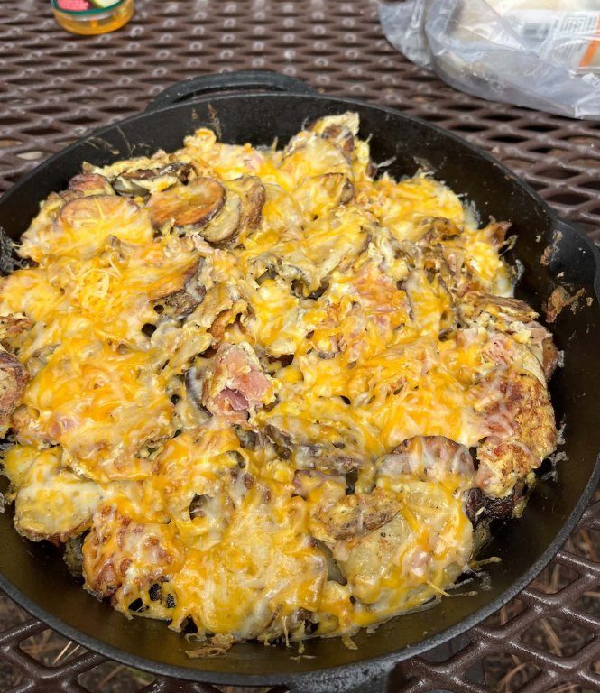 A cast-iron skillet of cheesy camp potatoes